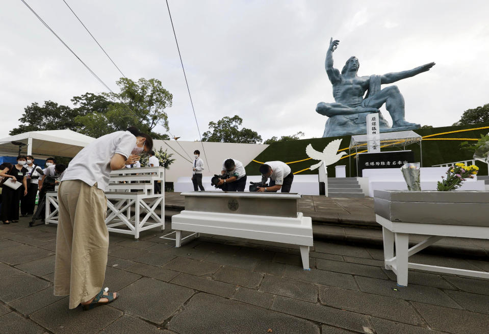 A woman prays for the victims of U.S. atomic bombing in front of the Statue of Peace at the Peace Park in Nagasaki, southern Japan Sunday, Aug. 9, 2020. Nagasaki marked the 75th anniversary of the atomic bombing on Sunday. (Kyodo News via AP)