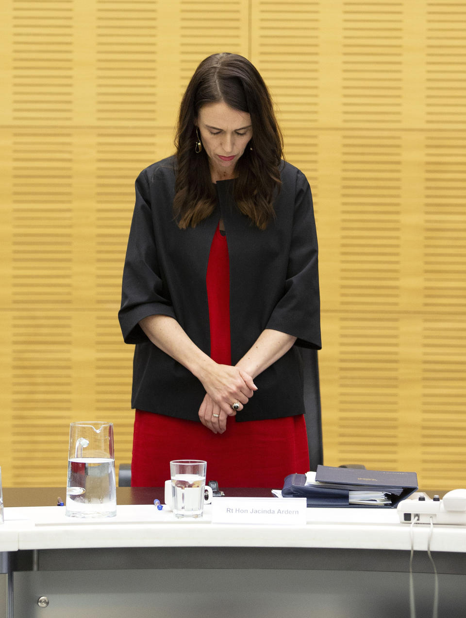 New Zealand Prime Minister Jacinda Ardern observes a moment of silence with her cabinet colleagues at the moment that a volcano erupted a week earlier, killing 18 people and leaving others with severe burns, in Wellington, New Zealand, Monday, Dec. 16, 2019. Ardern said that wherever people were in New Zealand or around the world, it was an opportunity to stand alongside those who had lost loved ones in the tragedy at White Island on Monday, Dec. 9. (Hagen Hopkins/Pool Photo via AP)