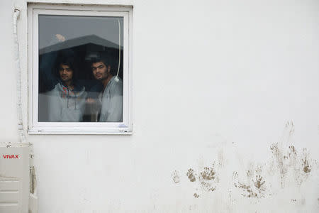 Two men look through a window inside the camp for refugees and migrants in the Belgrade suburb of Krnjaca, Serbia, January 16, 2018. Picture taken January 16, 2018 REUTERS/Djordje Kojadinovic