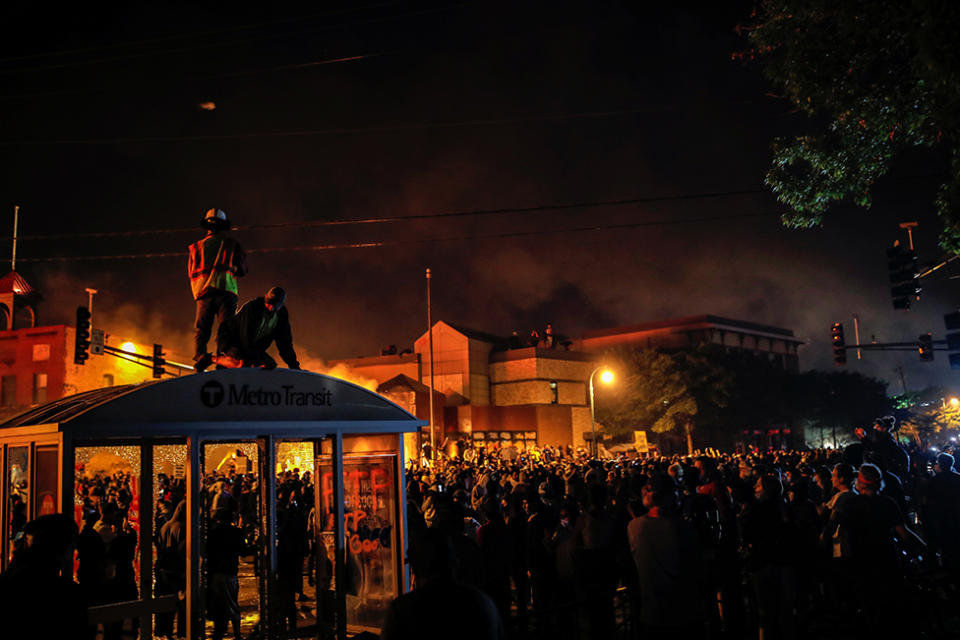 Los manifestantes se reúnen después de prender fuego a la entrada de una estación de policía