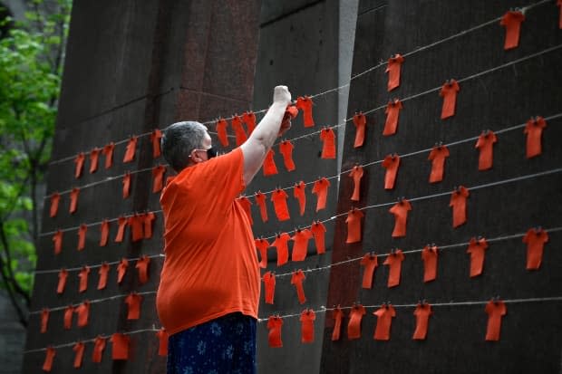 Orange fabric cut in the shape of shirts is pinned to string during a vigil in Ottawa June 5, 2021 to honour the 215 children whose remains were believed to found at the grounds of the former Kamloops Indian Residential School. A new federal holiday, the National Day of Truth and Reconciliation, will be marked on Sept. 30.  (Justin Tang/The Canadian Press - image credit)