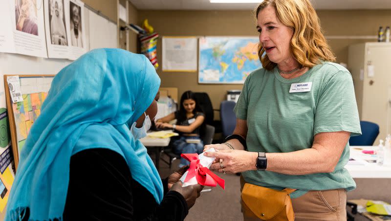Zinab, from Sudan, left, gets an apron from Amy Dott Harmer, executive director for the Utah Refugee Connection, at the Serve Refugees Sharehouse in South Salt Lake on Thursday, July 13, 2023.