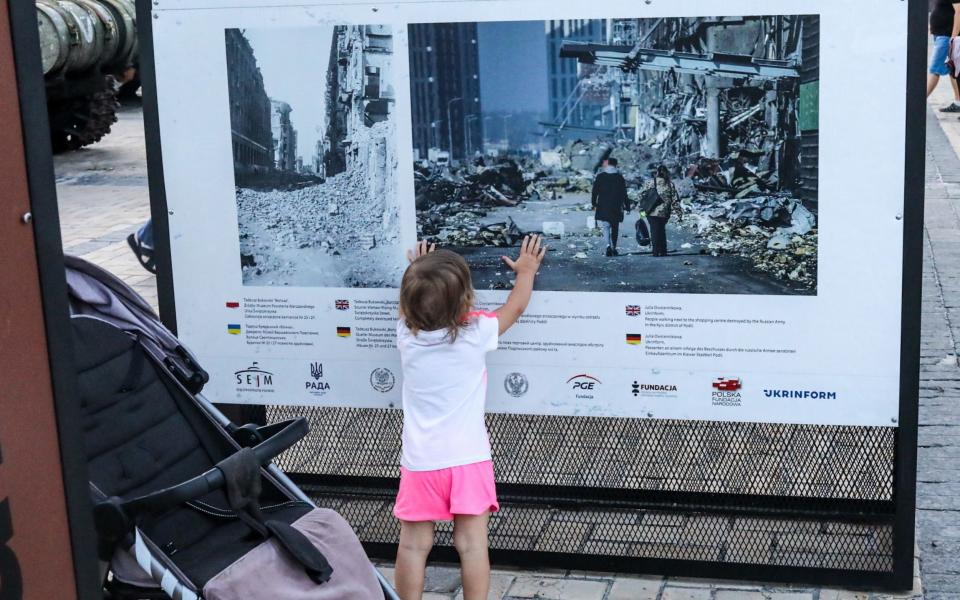 Photo shows a young child looking at an information board about the Russian invasion of Ukraine