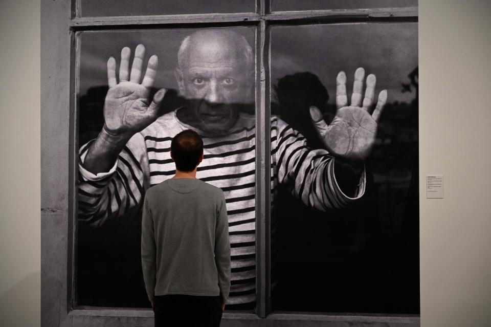 A man looks at a photograph by French photographer Robert Doisneau entitled "The Fate Line: Pablo Picasso at Vallauris, 1952." during the presentation of the photo-exhibition "Picasso, photographer's gaze", on June 5, 2019 at the Picasso Museum in Barcelona.