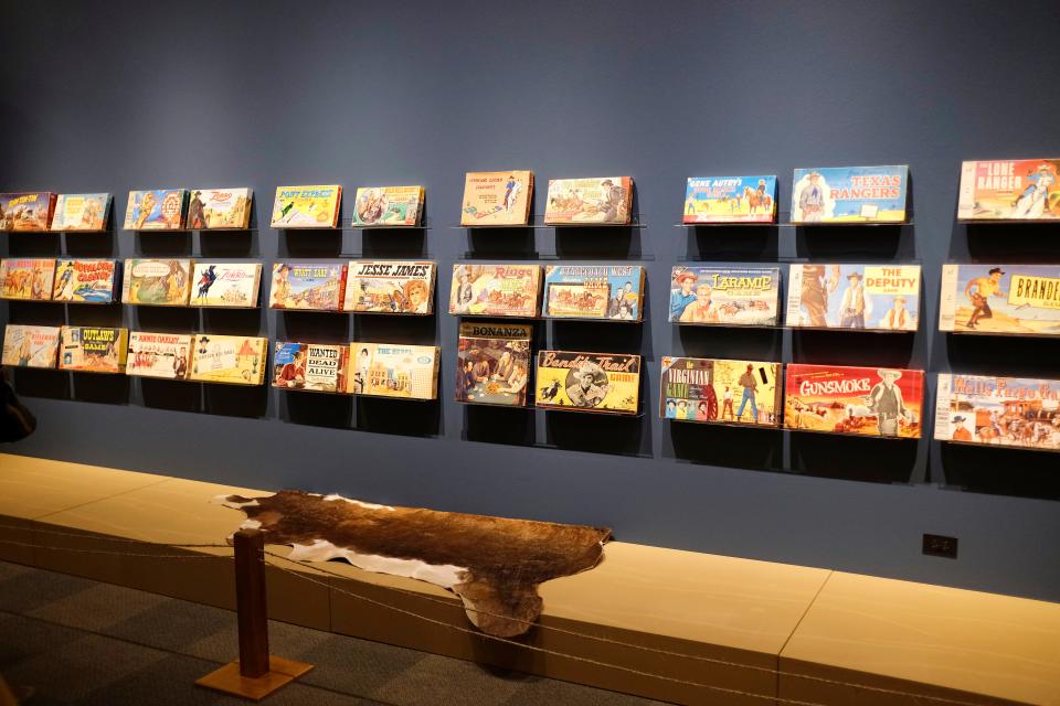 An array of Western-theme board games is displayed in the National Cowboy & Western Heritage Museum exhibit "Playing Cowboy" Friday, March 24, 2023, in Oklahoma City. On view through May 7, "Playing Cowboy" showcases Western books, costumes and toys for children.