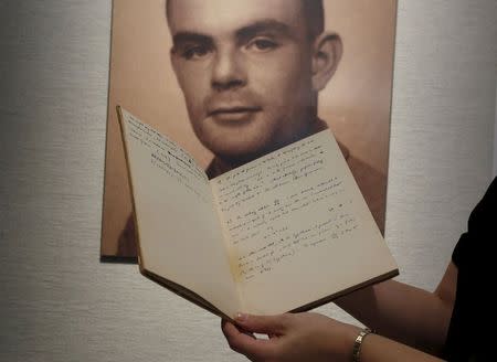 A notebook of British mathematician and pioneer in computer science Alan Turing is displayed in front of a photo of him during an auction preview in Hong Kong March 19, 2015. REUTERS/Bobby Yip