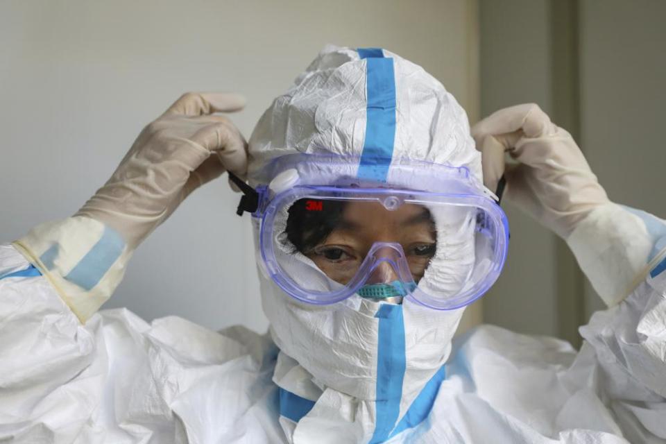 A doctor puts on a protective suit and goggles at a hospital in Wuhan.
