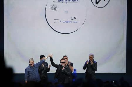 Apple CEO Tim Cook speaks with Bono from U2 during an Apple event announcing the iPhone 6 and the Apple Watch at the Flint Center in Cupertino, California, September 9, 2014. REUTERS/Stephen Lam