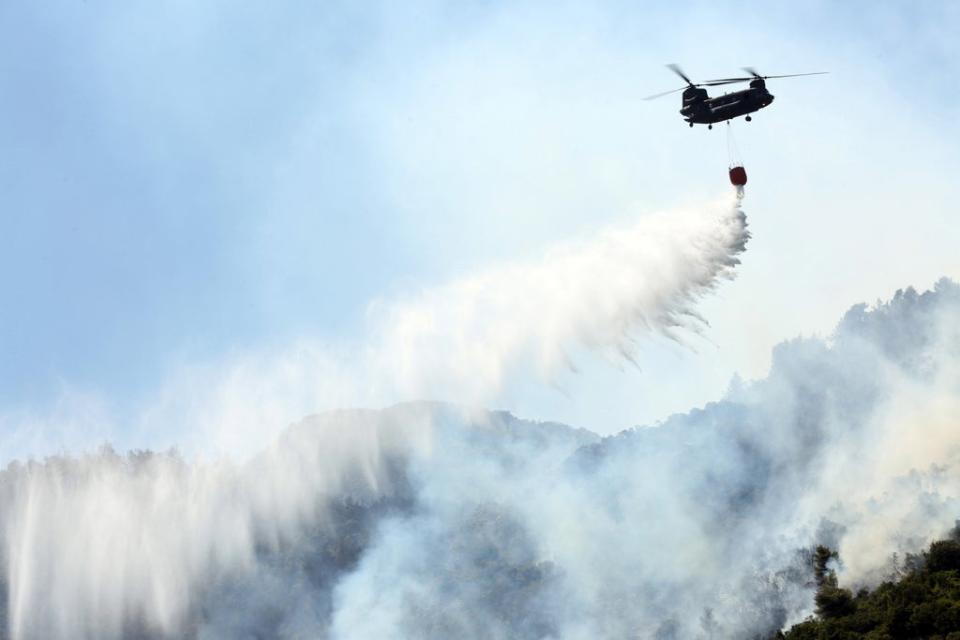 A Chinook douses a wildfire in the Malakassa area (EPA)