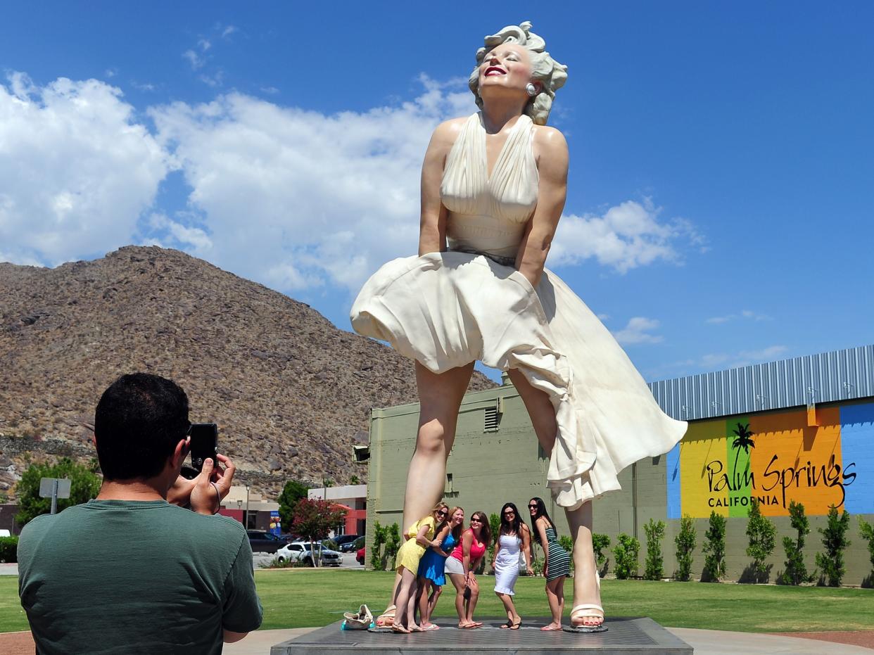 <p>Women pose for a photo beneath the 'Forever Marilyn' statue of actress Marilyn Monroe in Palm Springs, California, on August 4, 2012</p> (AFP via Getty Images)