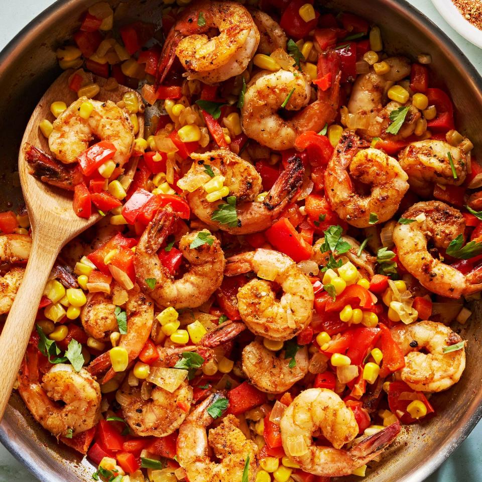 cajun spiced shrimp in a skillet with sliced bell peppers and corn