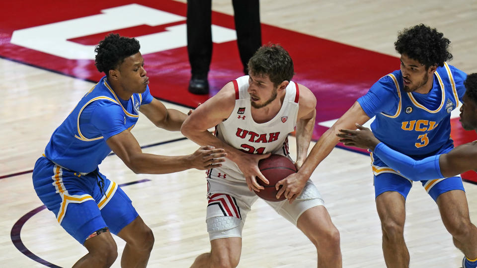 UCLA's Jaylen Clark, left, and Johnny Juzang (3) defend against Utah forward Riley Battin (21) during the first half of an NCAA college basketball game Thursday, Feb. 25, 2021, in Salt Lake City. (AP Photo/Rick Bowmer)