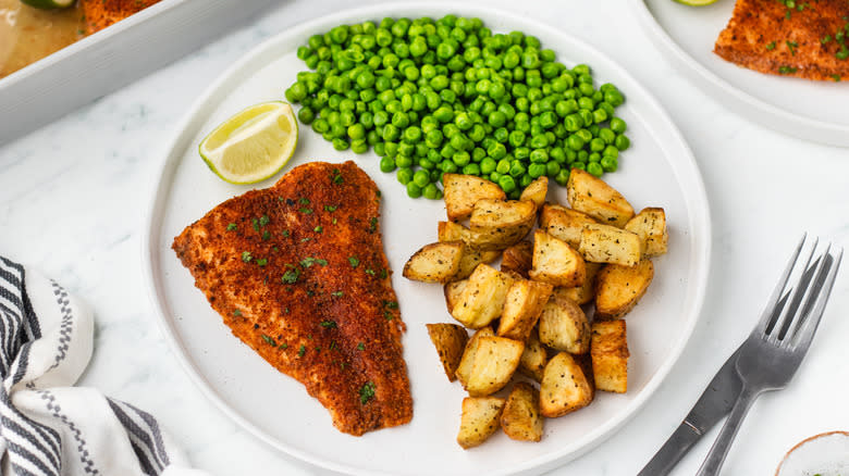 Chili lime tilapia with peas and potatoes on plate