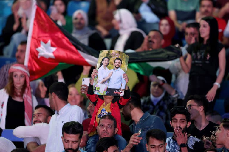 Un hombre sostiene un cartel que muestra al príncipe heredero jordano Hussein y a su prometida Rajwa al-Saif, durante la celebración de un concierto musical gratuito previo a la boda en el Estadio Internacional de Amán, el 29 de mayo de 2023.