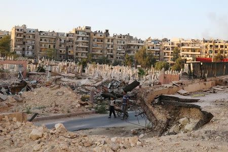 People walk near an over-crowded graveyard in the rebel held al-Shaar neighbourhood of Aleppo, Syria October 6, 2016. REUTERS/Abdalrhman Ismail