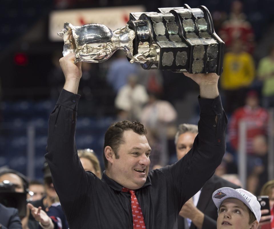 Oshawa Generals head coach D.J. Smith raises the Memorial Cup trophy after they won the tournament 2-1 in overtime against the Kelowna Rockets Sunday, May 31, 2015 at the Memorial Cup final in Quebec City. (Jacques Boissinot/The Canadian Press via AP) MANDATORY CREDIT