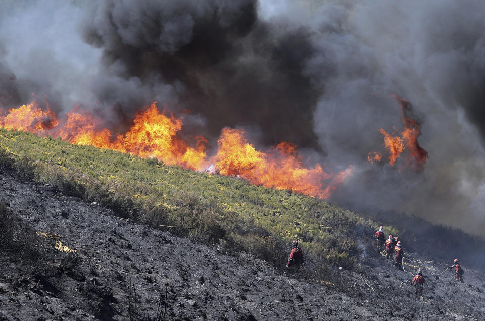 Firefighters try to extinguish a forest fire in Bouzas