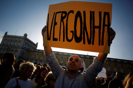 A woman holds a poster saying "shame" during a demonstration in a tribute to the victims of the deadly fires in Portugal, in Praca do Comercio square, downtown Lisbon, Portugal October 21, 2017. REUTERS/Pedro Nunes