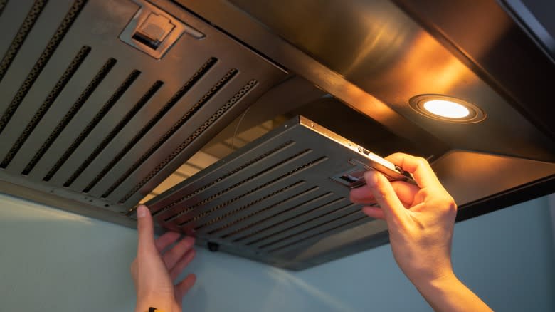 Person removing filter on range hood