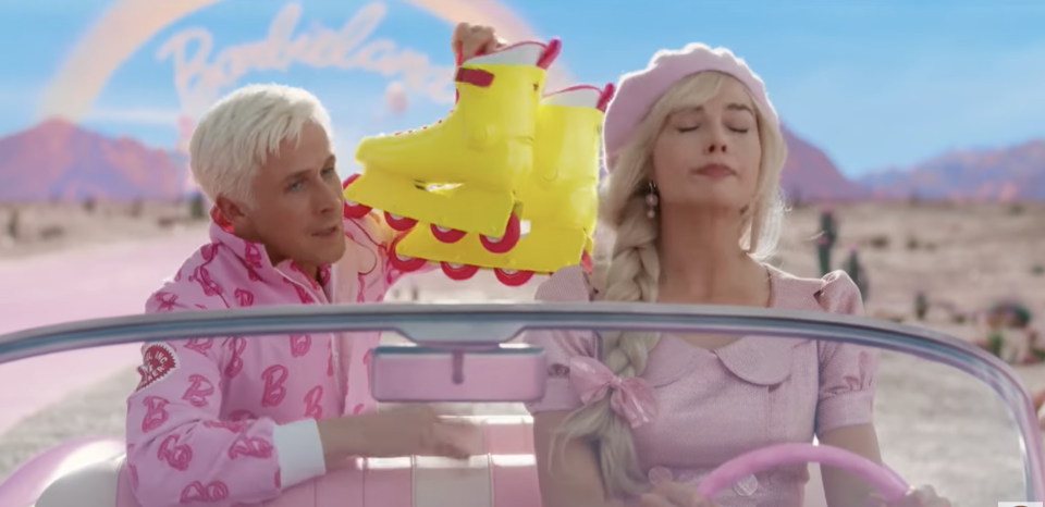 Barbie and Ken from the "Barbie" movie are in the car. Ken is holding up roller skates