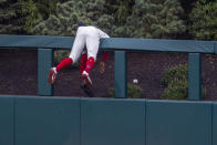 Philadelphia Phillies center fielder Roman Quinn hangs over the wall trying to catch a home run hit by St. Louis Cardinals' Paul DeJong (11) during the third inning of a baseball game, Saturday, April 17, 2021, in Philadelphia. (AP Photo/Laurence Kesterson)