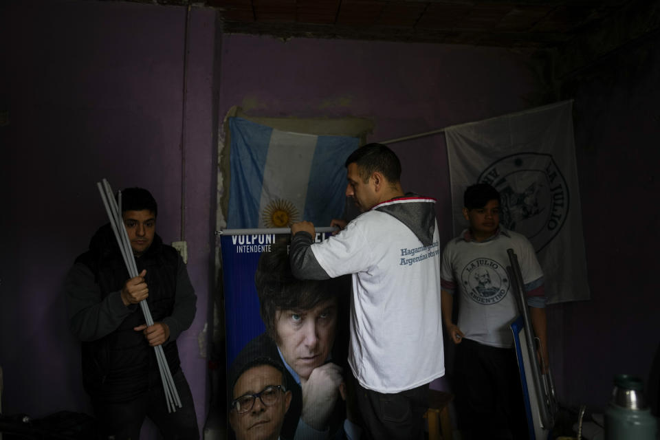 Andrés Ferreira, simpatizante del aspirante presidencial Javier Milei, enrolla unos carteles de campaña del candidato, en su casa del barrio de Fiorito en Buenos Aires, Argentina, el sábado 23 de septiembre de 2023. Ferreira, que trabaja como repartidor en una plataforma digital, también hace promoción por Milei en la municipalidad de Lomas de Zamora de Buenos Aires. (AP Foto/Natacha Pisarenko)