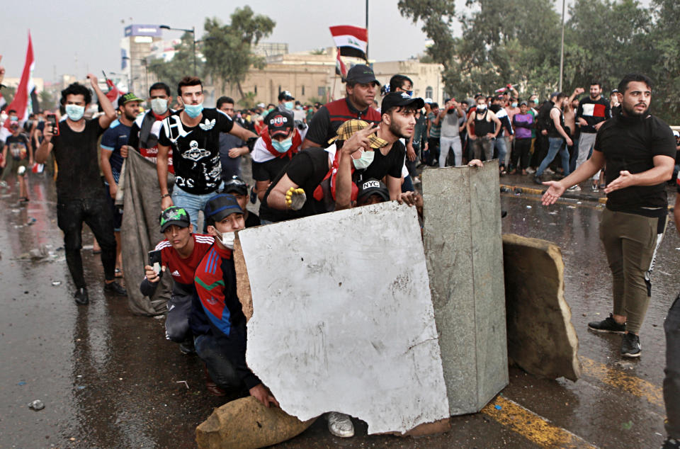 Anti-government protesters take cover while Iraq security forces fire during a demonstration in central Baghdad, Iraq, Friday, Oct. 25, 2019. Iraqi police fired live shots into the air as well as rubber bullets and dozens of tear gas canisters on Friday to disperse thousands of protesters on the streets of Baghdad, sending young demonstrators running for cover and enveloping a main bridge in the capital with thick white smoke. (AP Photo/Khalid Mohammed)