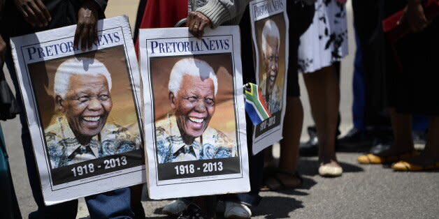 People hold portraits of Nelson Mandela as South Africans stand in line to pay their respect to South African former president Nelson Mandela laying in state at the Union Buildings on December 12, 2013 in Pretoria. South Africans will get a second chance Thursday to pay their last respects to Nelson Mandela, a day after his distraught widow joined thousands of mourners at his open coffin. Mandela, the revered icon of the anti-apartheid struggle in South Africa and one of the towering political figures of the 20th century, died in Johannesburg on December 5 at age 95.         AFP PHOTO / STEPHANE DE SAKUTIN        (Photo credit should read STEPHANE DE SAKUTIN/AFP/Getty Images) (Photo: )