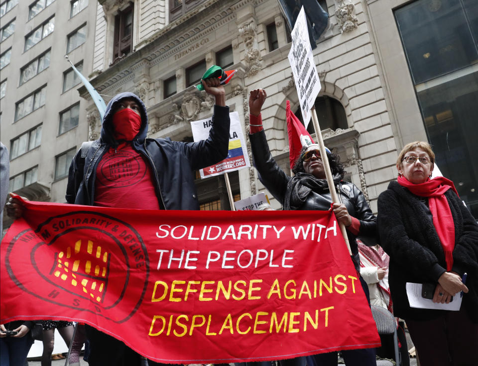 FILE - In this Wednesday, May 1, 2019 file photo, people from Harlem Solidarity and Defense, protesting displacement from gentrification of their neighborhood, hold a banner during a May Day rally in front of 40 Wall Street, a Trump-owned property in New York. President Donald Trump is facing a reported $421 million in loans due in the next four years, a sum that’s been portrayed as a tightening vise on his finances and an ethical minefield for his administration. But financial experts say Trump has plenty of options and assets to pay off that debt, starting with a portfolio that includes office towers, golf courses and branding deals that's been valued at $3.6 billion. (AP Photo/Kathy Willens, File)