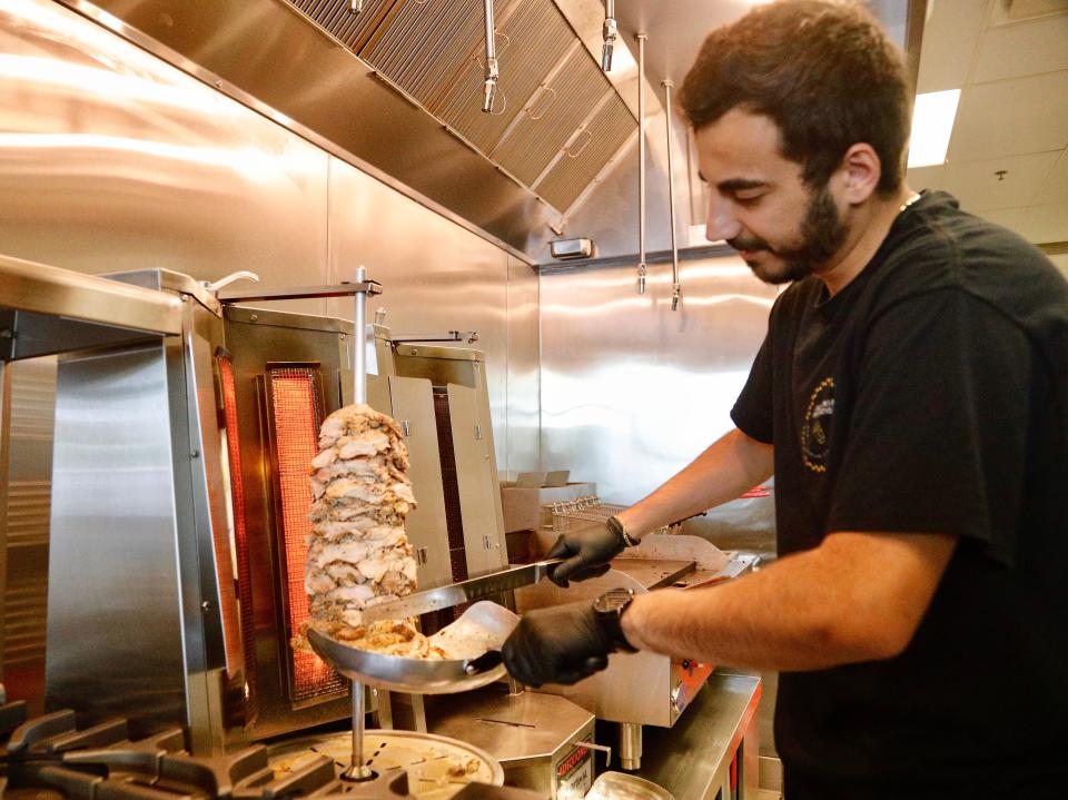 California Pita Station partner Tee Mough trims chicken from a shawarma that rotates on a vertical rotisserie or spit on Thursday, June 16, 2022. The restaurant closed in 2023.