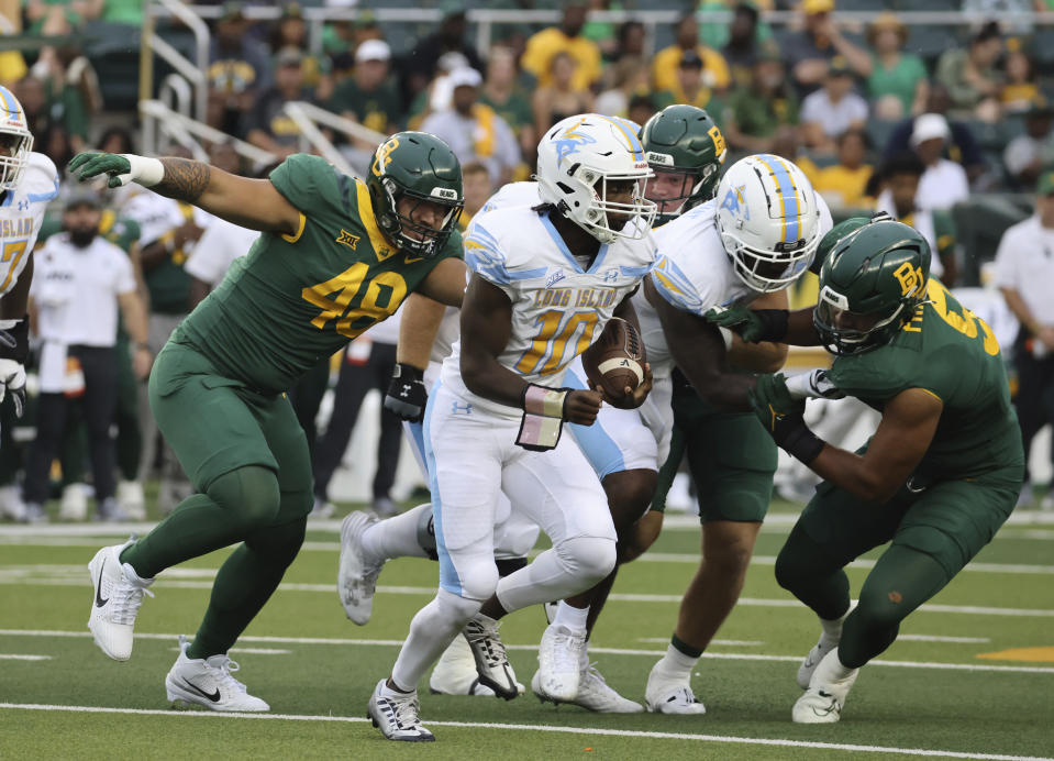 Long Island quarterback Chris Howell runs out of the pocket while getting pressured by Baylor defensive linemen Treven Ma'ae (48) and TJ Franklin (9) during the first half of an NCAA college football game, Saturday, Sept. 16, 2023, in Waco, Texas. (Rod Aydelotte/Waco Tribune-Herald via AP)