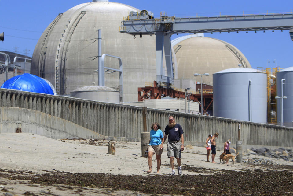FILE - This file photo taken June 30, 2011 shows beach-goers walking on the sand near the San Onofre nuclear power plant in San Clemente , Calif. The twin reactors at the plant have been idled while investigators determine why tubing carrying radioactive water is eroding at an unusual rate, and the Nuclear Regulatory Commission chairman will visit the plant Friday, April 6, 2012, to highlight the agency's concern over the ailing equipment. (AP Photo, Lenny Ignelzi, File)