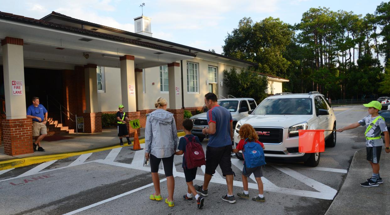 While a crossing guard stops traffic, a couple lead their sons, ages 6 and 8, into Hendricks Avenue Elementary School in this photo from 2015. Hendricks Avenue is among 15 school district- or charter-run elementaries in Duval County recently labeled "schools of excellence" by Florida's Board of Education.