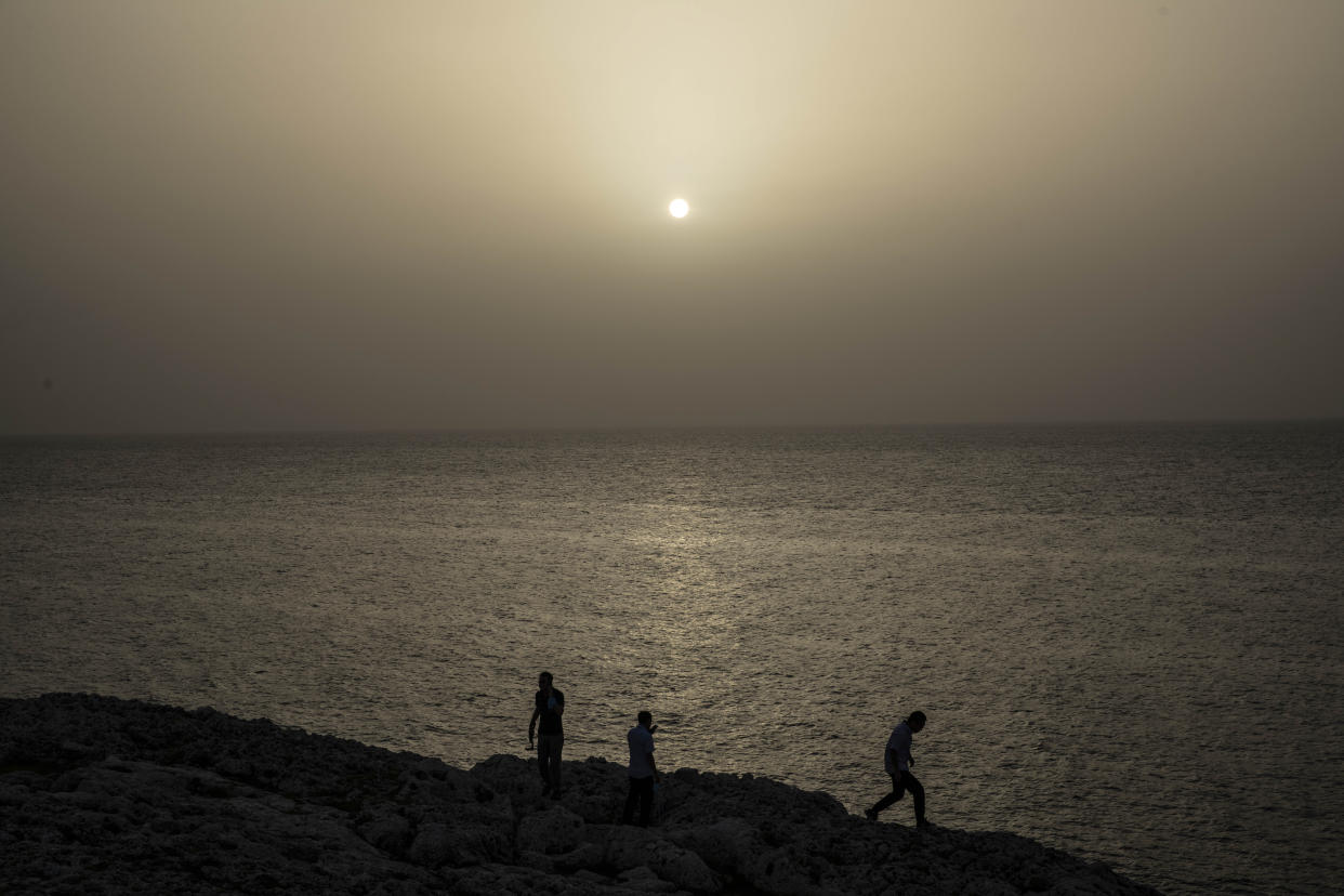 People watch the sunset while a cloud of Sahara dust hangs in the air in Havana on Wednesday, June 24, 2020. The massive cloud of dust is blanketing the Caribbean as it heads to the United States. (AP Photo / Ramon Espinosa)