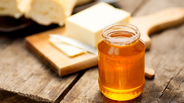 Jar of honey next to stick of butter 