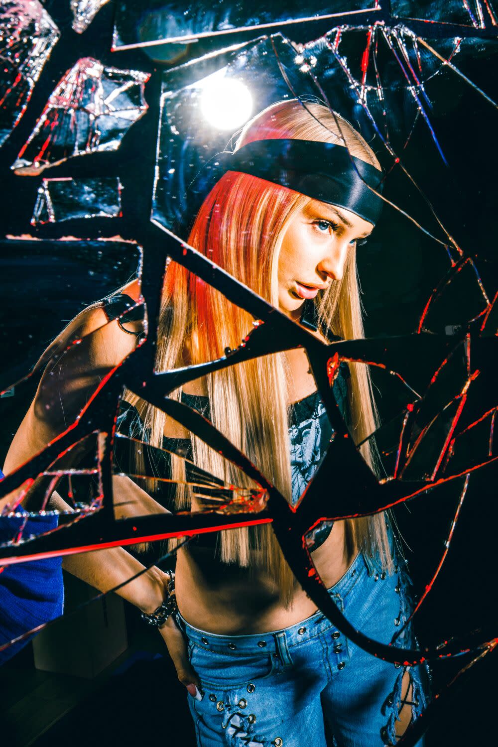 A woman stands in front of broken mirrored glass