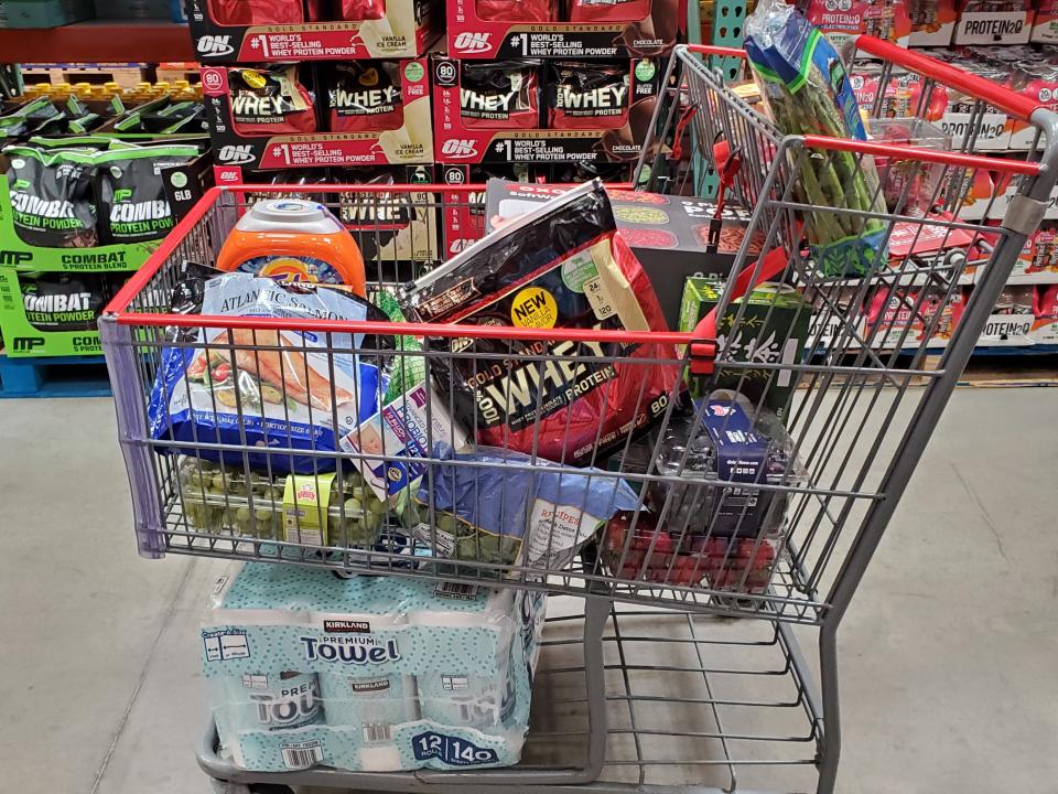 A full Costco cart with protein powder and produce