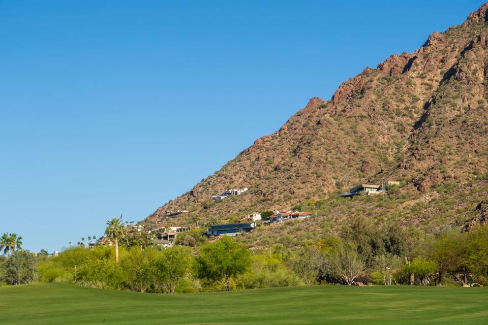 Millionaire homes on a mountain above a golf course in Paradise Valley, Arizona, on a blue-skyed day