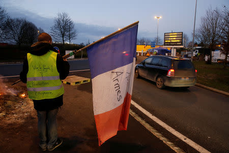 A protester wearing a yellow vest, the symbol of a French drivers' protest against higher diesel fuel prices, holds a flag at the approach to the A2 Paris-Brussels Motorway, in Fontaine-Notre-Dame, France, December 4, 2018. REUTERS/Pascal Rossignol