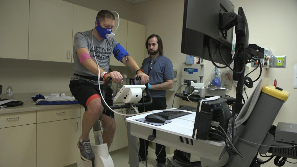 In this Nov. 18, 2019 image from video, Zach Ault of Paducah, Ky., is connected to medical monitors during an exercise test at the National Institutes of Health's hospital in Bethesda, Md. Ault has ME/CFS, what once was called "chronic fatigue syndrome," and is part of a unique study aiming to uncover clues to how the mysterious disease steals patients' energy. At center is Brice Calco, a research trainee with NIH's National Institute of Neurologic Disorders and Stroke. (AP Photo/Federica Narancio)