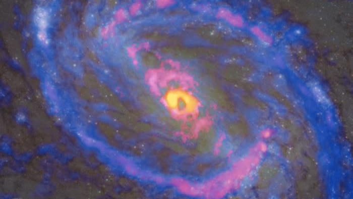  A spiral galaxy with an orange/yellow center and arms with pink and blue. 