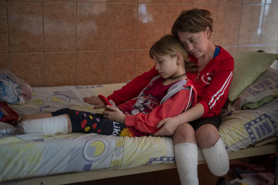 Natasha Stepanenko, de 43 años, se sienta en su cama con su hija Yana, de 11 años, el sábado 15 de mayo de 2022 en un hospital público de Leópolis, Ucrania. El 8 de abril, un misil impactó en la estación de tren de la ciudad oriental de Kramatorsk, donde Natasha, Yana y su hermano gemelo Yarik planeaban tomar un tren de evacuación en dirección al oeste con la esperanza de ponerse a salvo. Yana perdió dos piernas, una por encima del tobillo y la otra por encima de la espinilla. Natasha perdió la pierna izquierda por debajo de la rodilla. (AP Foto/Emilio Morenatti)