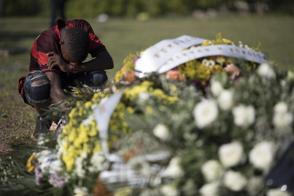 A friend, wearing a Flamengo soccer kit, grieves at the grave of the young soccer player Arthur Vinicius, one of the victims of a fire at a Brazilian soccer academy, after his burial in Volta Redonda, Brazil, Saturday, Feb. 9, 2019. A fire early Friday swept through the sleeping quarters of an academy for Brazil's popular professional soccer club Flamengo, killing several and injuring others, most likely teenage players, authorities said. (AP Photo/Leo Correa)