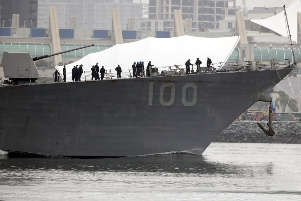 Crew members look on as the USS Kidd passes downtown San Diego as it returns to Naval Base San Diego, Tuesday, April 28, 2020, as seen from Coronado, Calif. As the American destroyer heads home with an outbreak in cases of COVID-19, relatives and friends of the 350 crew members prayed for their health while Navy officials vowed to keep the outbreak, the second to strike a Navy vessel at sea, from spreading. (AP Photo/Gregory Bull)