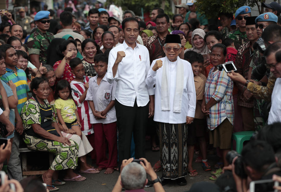 Indonesian President Joko Widodo, center left, and his running mate Ma'ruf Amin gesture as they pose for photographers after declaring their victory in the country's presidential election, at a slum in Jakarta, Indonesia, Monday, Tuesday, May 21, 2019. Widodo has been elected for a second term, official results showed, in a victory over a would-be strongman who aligned himself with Islamic hard-liners and vowed Tuesday to challenge the result in the country's highest court. (AP Photo/Dita Alangkara)