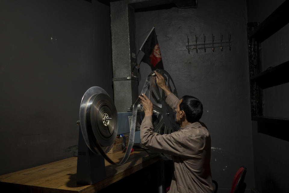 Rahmatullah Ezati plays back a film roll in the projectionist room of the Ariana Cinema in Kabul, Afghanistan on Monday, Nov. 8, 2021. The cinema's staff still show up at work every day hoping they will eventually get paid, despite the Taliban's orders to stop operating. (AP Photo/Bram Janssen)