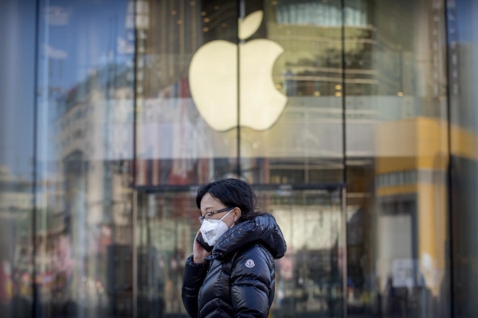 A woman wears a face mask as she walks past an Apple store that is temporarily closed due to health concerns in Beijing, Tuesday, Feb. 4, 2020. Apple announced that it will temporarily close all of its stores in China due to a virus outbreak. (AP Photo/Mark Schiefelbein)