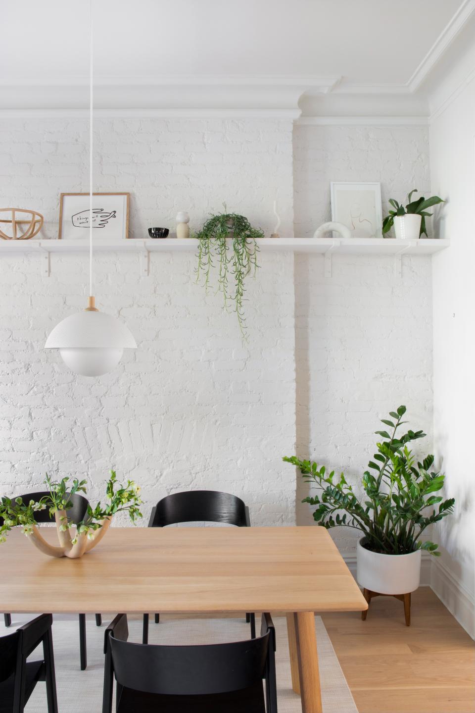 White brick and a single linear shelf are key elements of a streamlined dining area devoid of visual clutter.