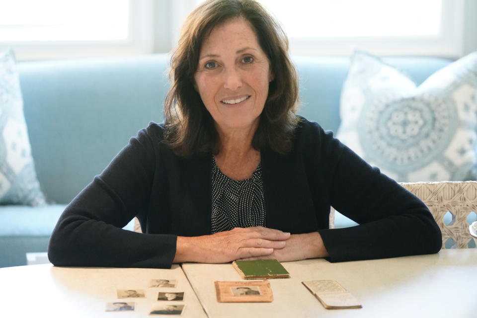 Anna Salton Eisen, the daughter of Holocaust survivors, poses with photos and a notebook her father kept after his internment in Nazi work camps, during an interview in Westlake, Texas on Wednesday, Oct. 6, 2021. Eisen's father, George Lucius Salton, was a survivor of ten different concentration camps and wrote a book about his survival through the Holocaust, and from photos, notes he kept and details in his book, Eisen has tracked down the survivors families to meet for their first joint gathering, both in-person and by a Zoom video call, to share memories and information. (AP Photo/LM Otero)