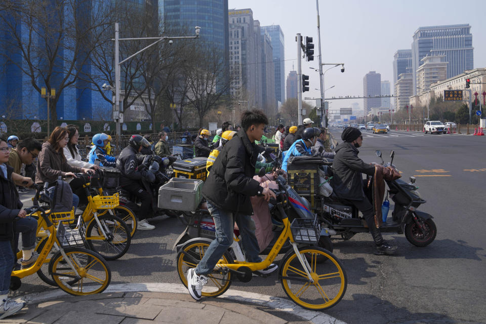 Motorists and cyclists cross at a main business district in Beijing, China, Friday, March 15, 2024. (AP Photo/Tatan Syuflana)